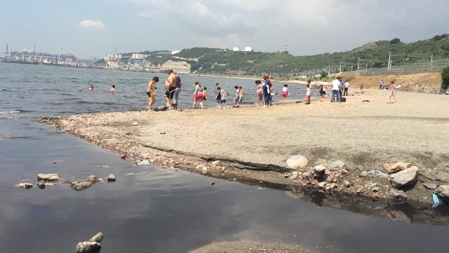 Kömür karası akan derenin yanında denize giriyorlar